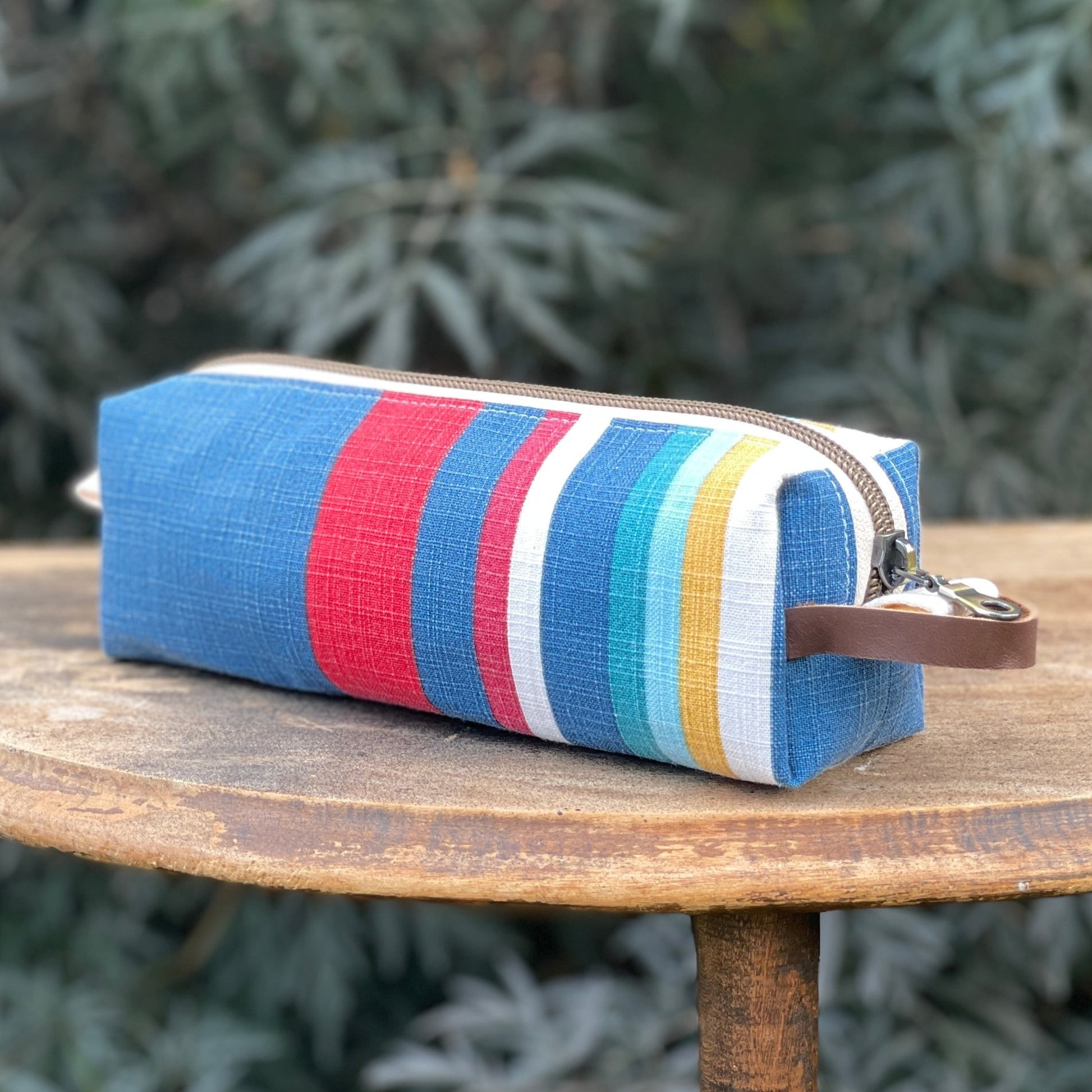 Striped pouch with colorful pattern on a wooden table outdoors