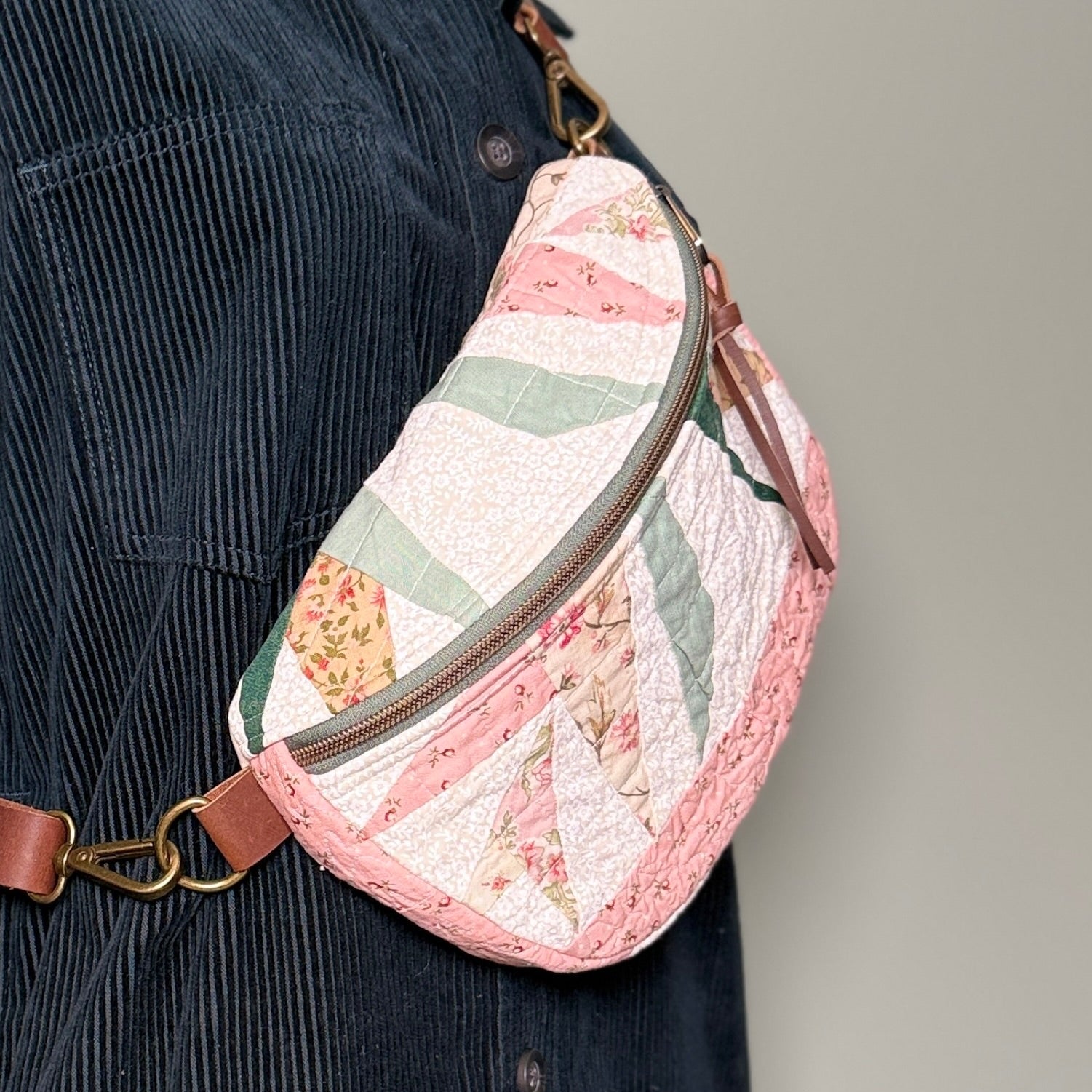 Quilted waist bag with floral pattern worn by a person against a neutral background